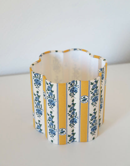 Abat-jour forme fleur à tissu blanc cassé, rayures jaunes et motifs floraux bleus.
