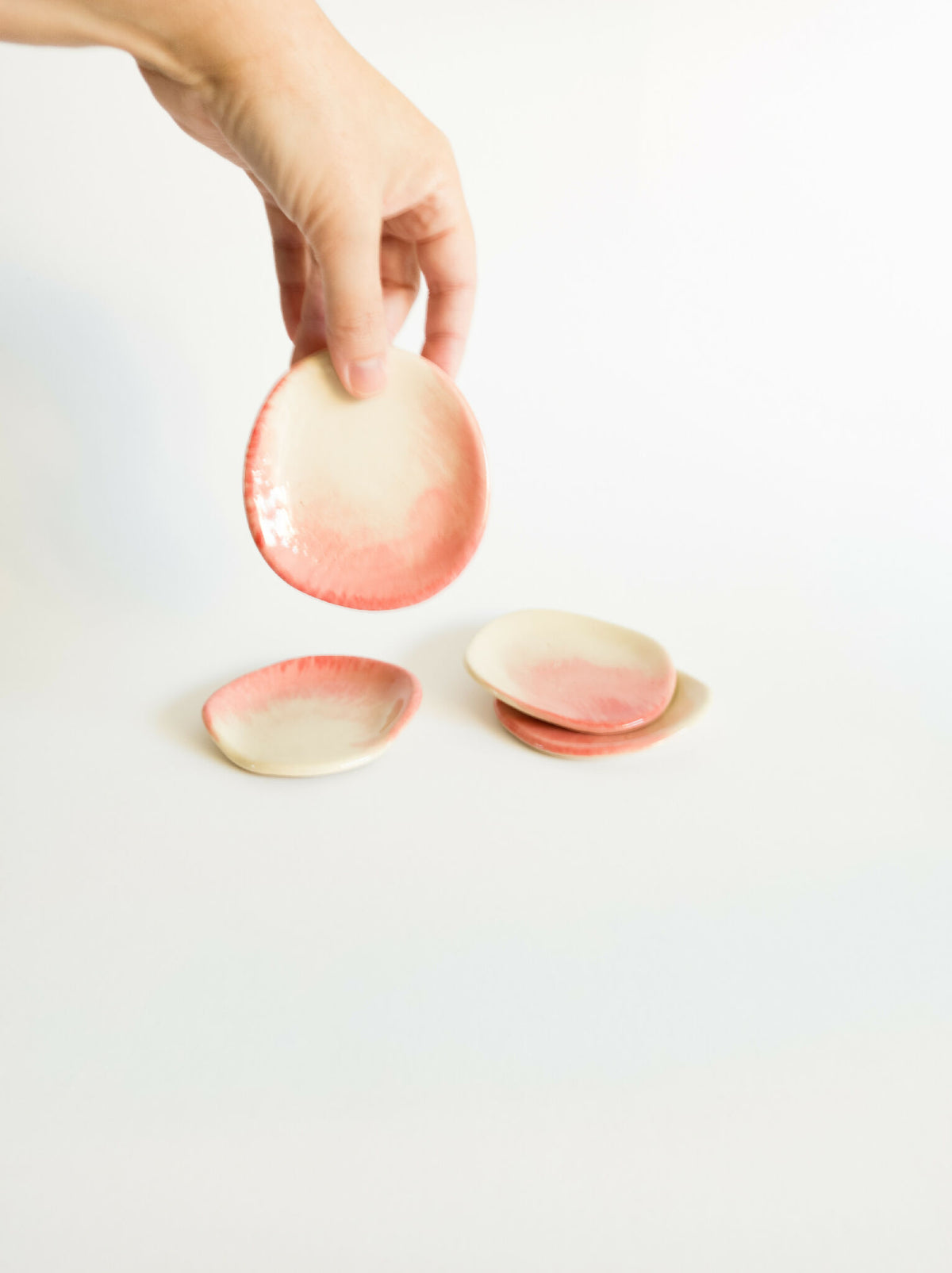 Repose-cuillère ovale en grès, rose pâle et beige, cuillère tenue par une main