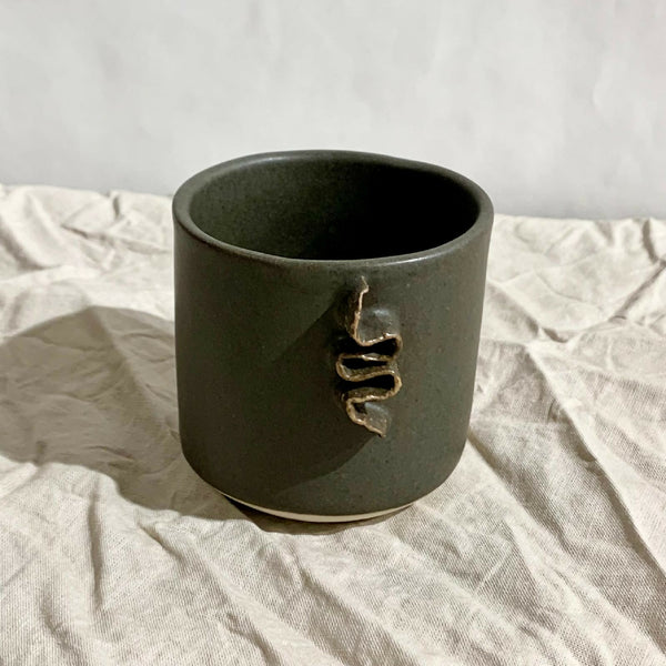 Tasse à café vert foncé avec motif doré sur le devant.