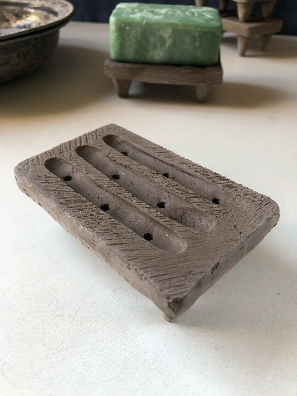Porte-savon en bois gris texturé avec rainures et trous de drainage pour savon