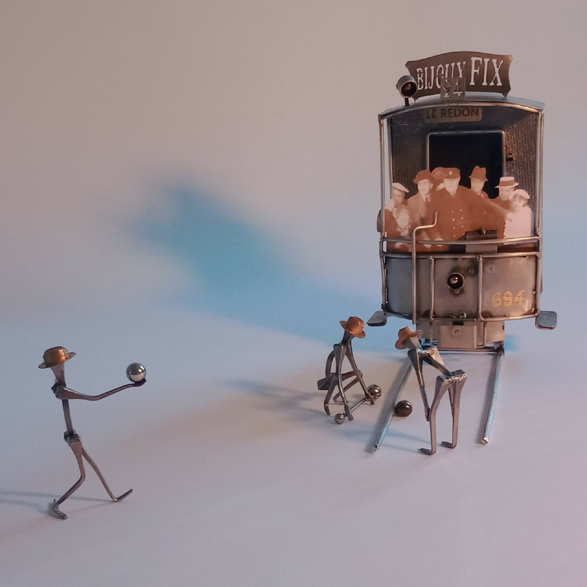 Sculpture miniature en métal : cabine à personnages et deux figurines assises