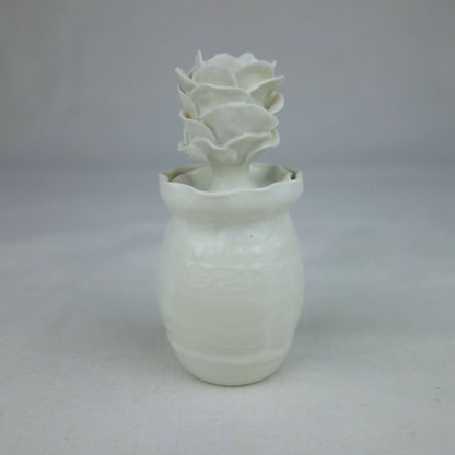 Vase en céramique blanc, forme cylindrique avec fleurs en relief sur le dessus.