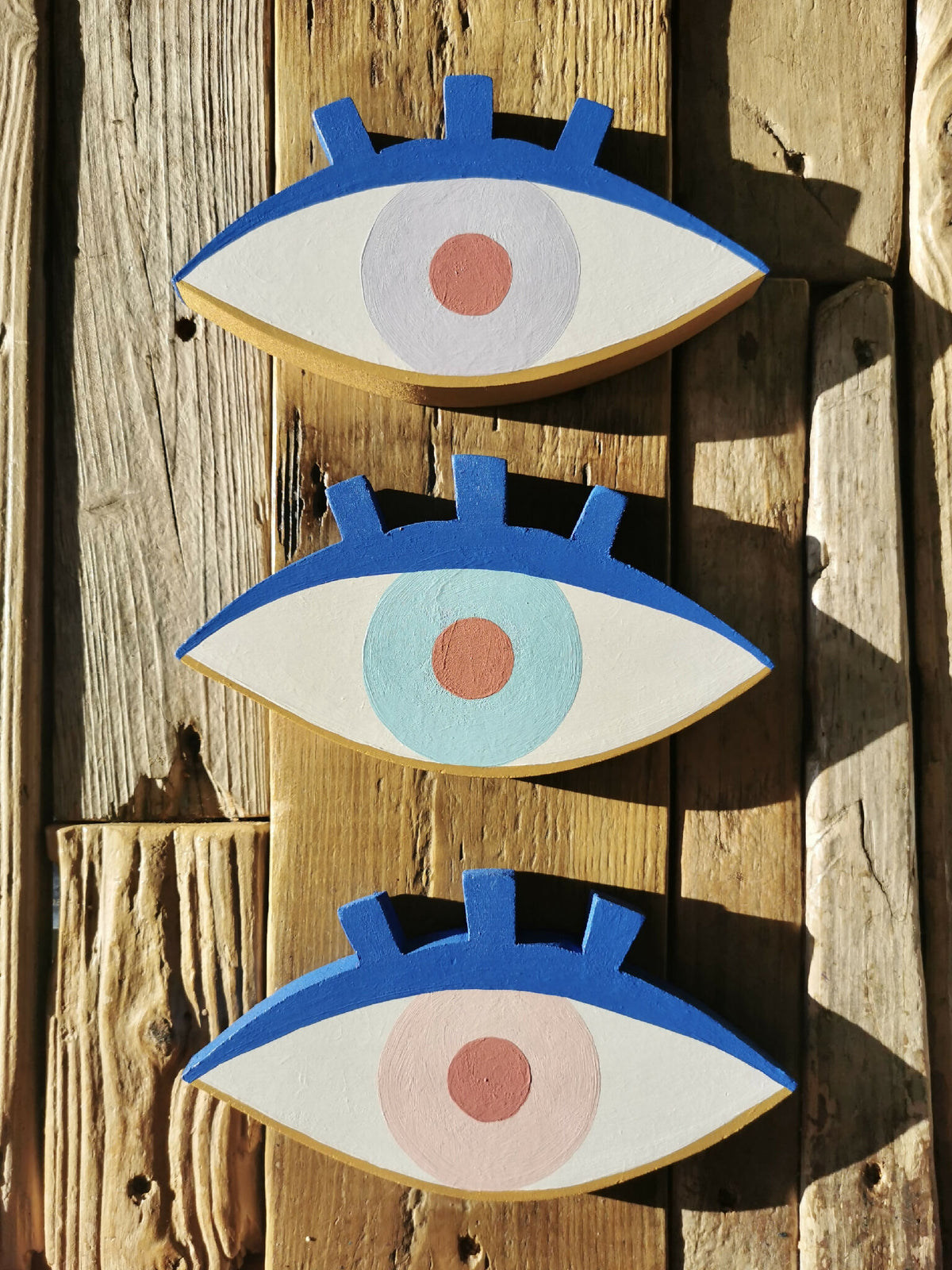 Trio de décorations œil en bois bleu, iris bleu clair et pupille rouge.