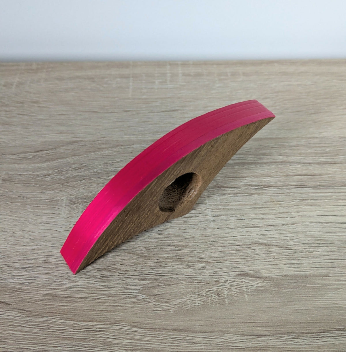 Bague de lecture en marqueterie de paille rose, vue de côté sur surface en bois