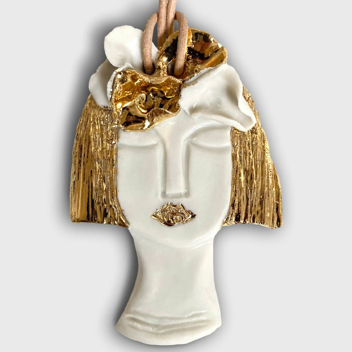 Pendentif buste blanc avec visage doré, franges et cordon brun
