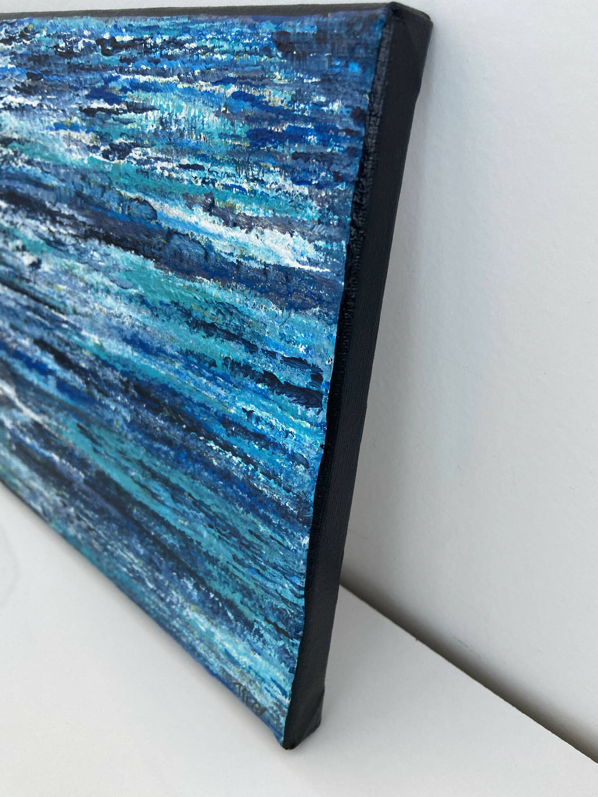 Tableau abstrait bleu nuit, vue en angle, bord noir et textures marquées de peinture.