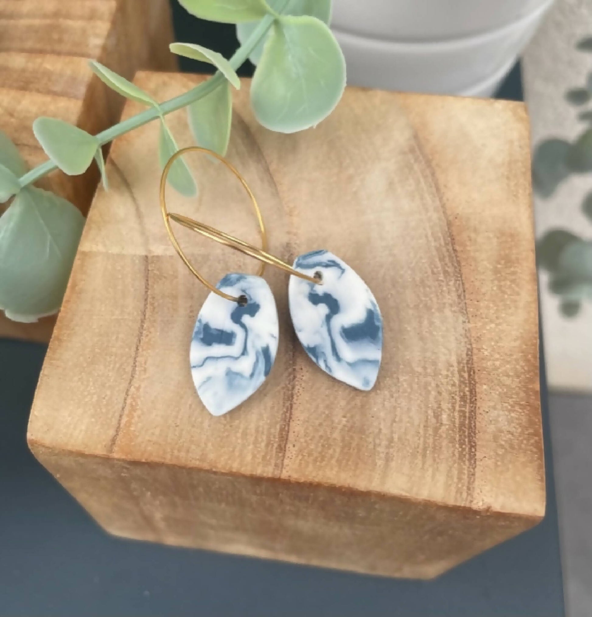 Créoles dorées et pendentifs goutte bleu marbré, vue de trois-quarts.