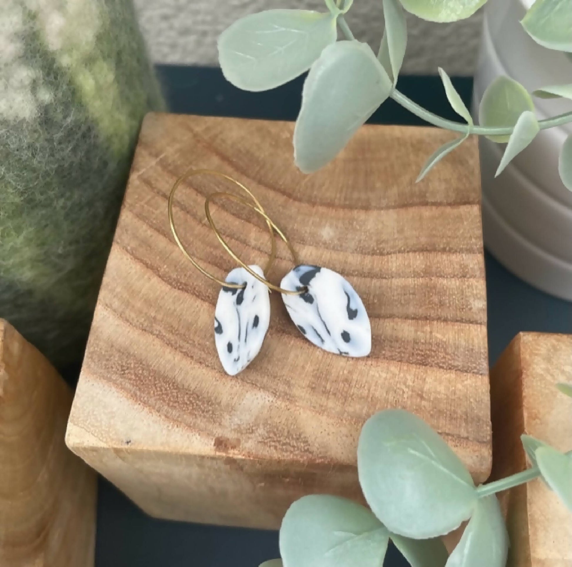 Boucles créoles dorées avec pendentifs goutte bleu marbré, détail du motif.