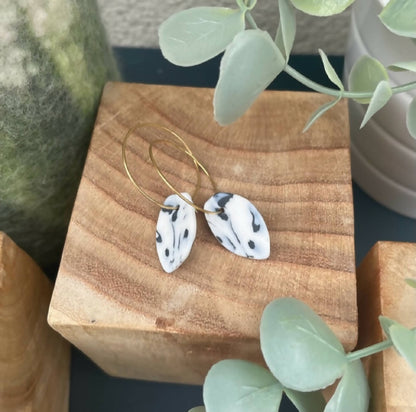 Boucles créoles dorées avec pendentifs goutte bleu marbré, détail du motif.