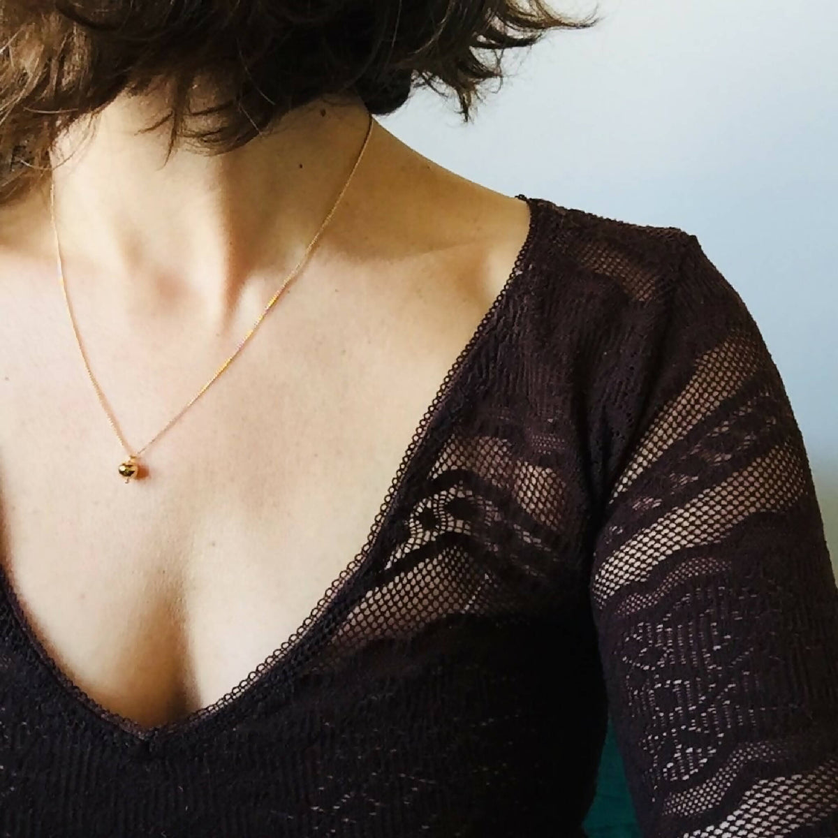Collier pendentif rond doré sur décolleté noir