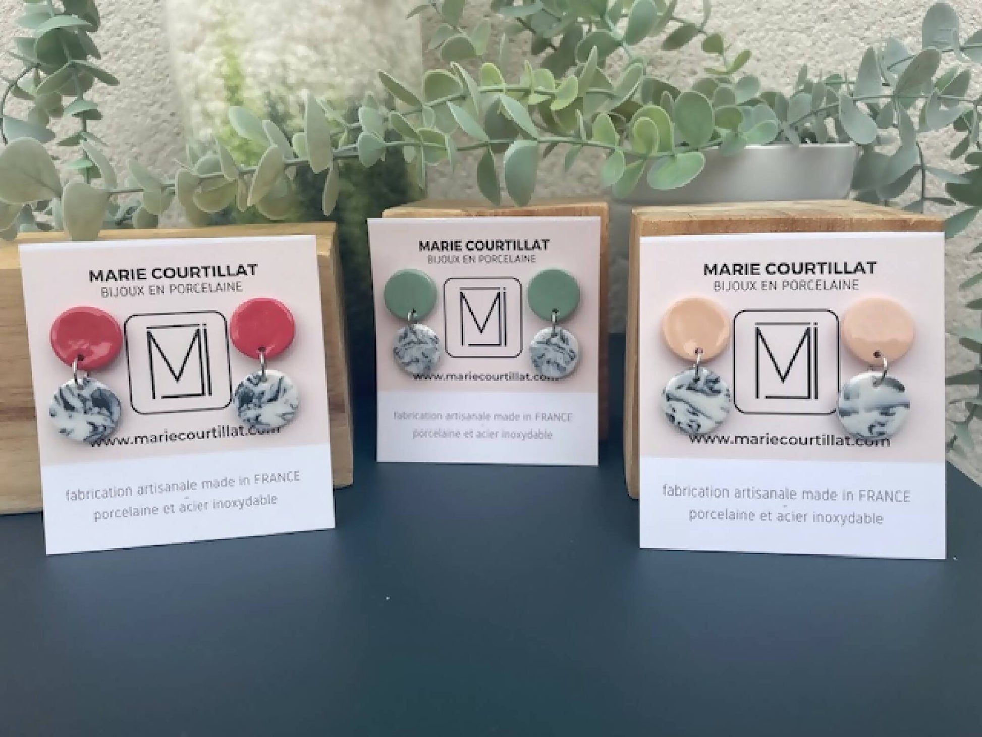 Trois paires de boucles d’oreilles en porcelaine : rouge, vert et rose sur présentoir