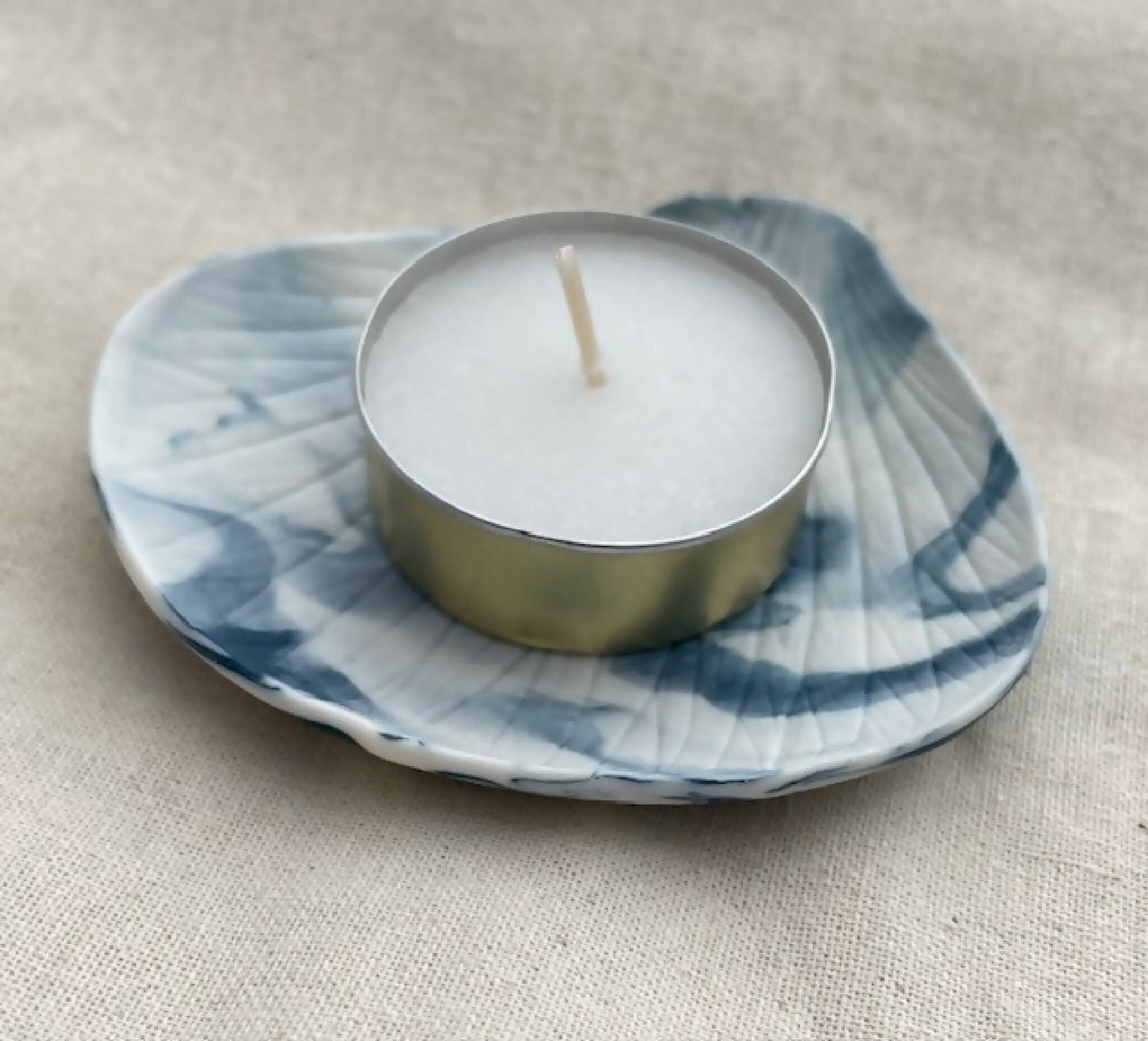 Bougeoir porcelaine marbrée bleu: coupelle ondulée, bougie blanche sur base dorée.