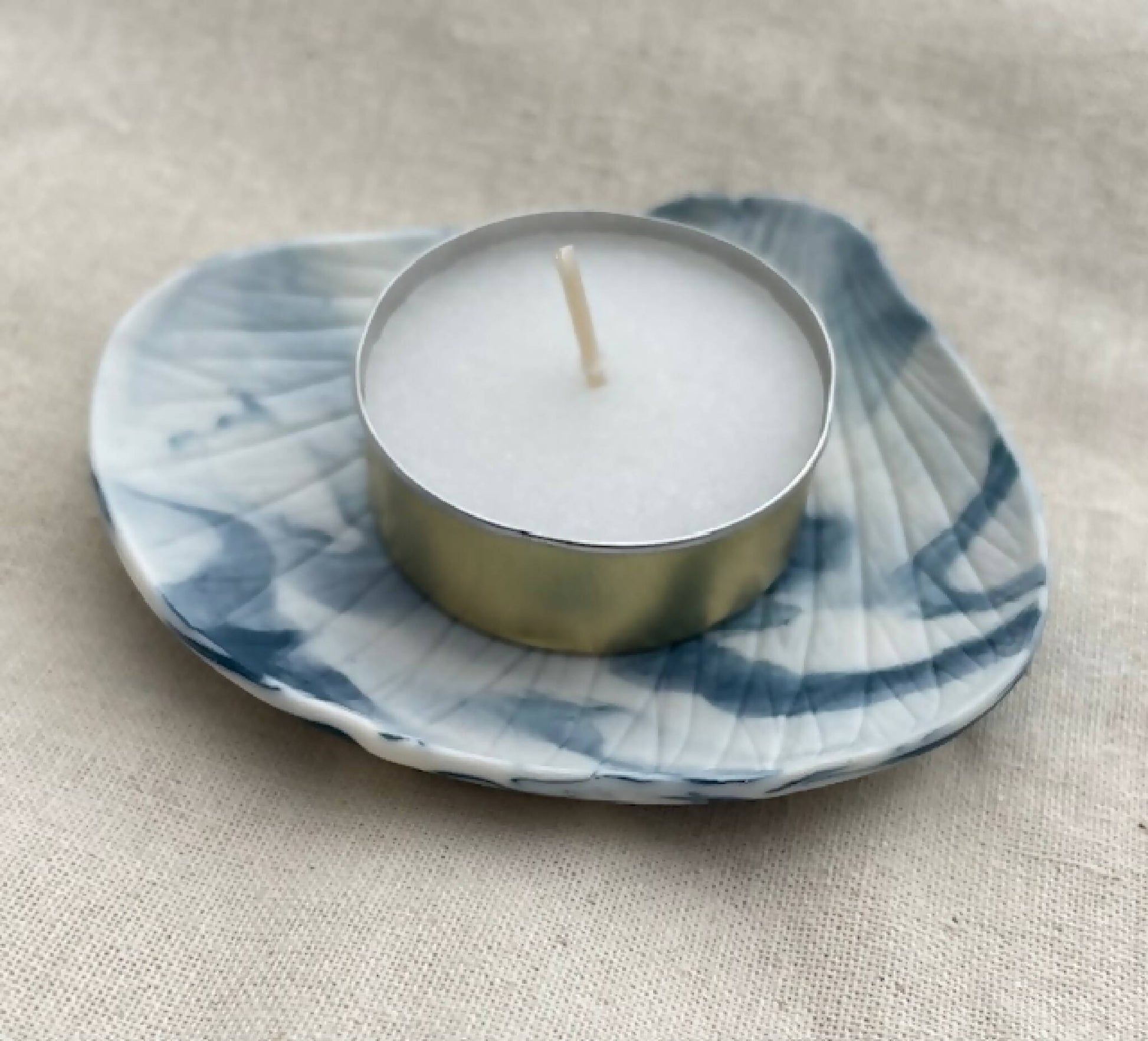 Bougeoir porcelaine marbrée bleu: coupelle ondulée, bougie blanche sur base dorée.