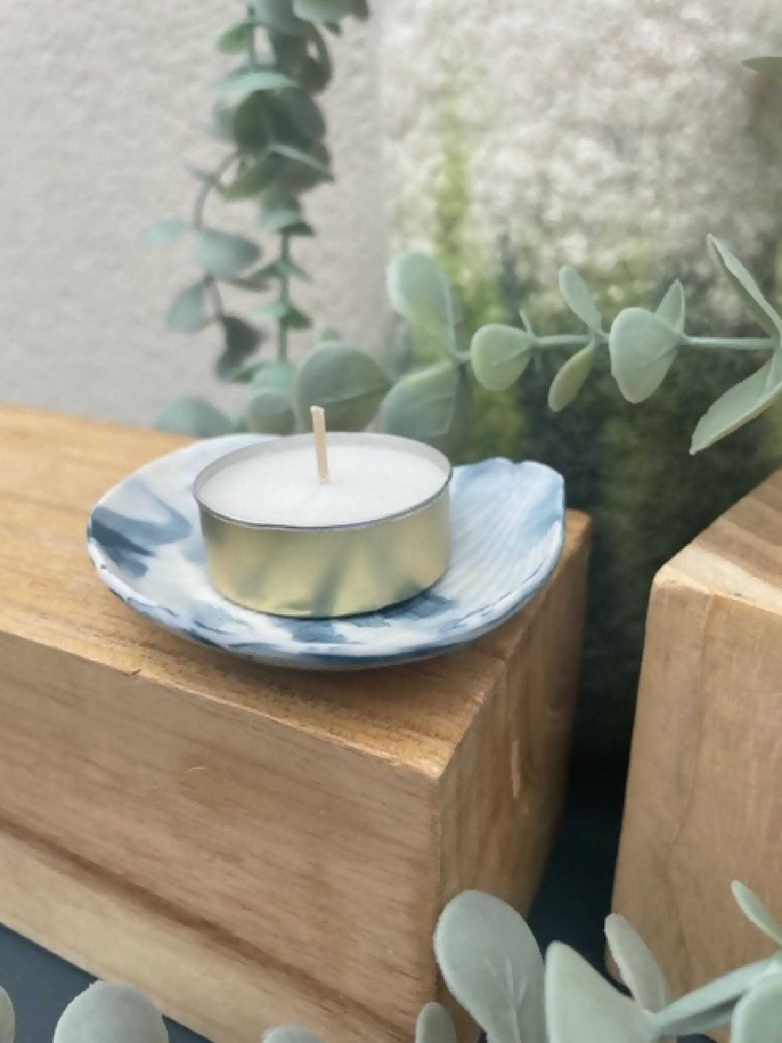 Bougeoir en porcelaine marbrée bleu, coupelle ronde, bougie blanche sur base dorée.