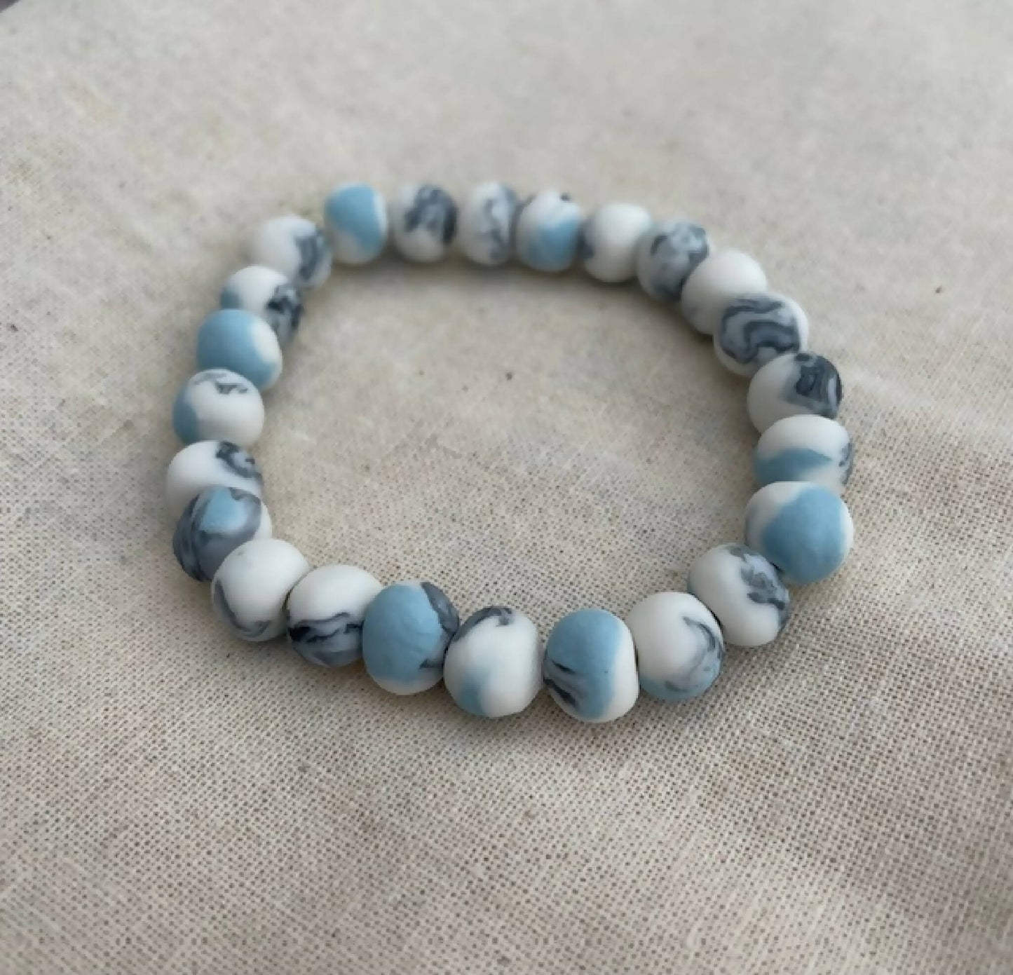 Bracelet femme en perles de porcelaine bleu clair et blanches, motif marbré.