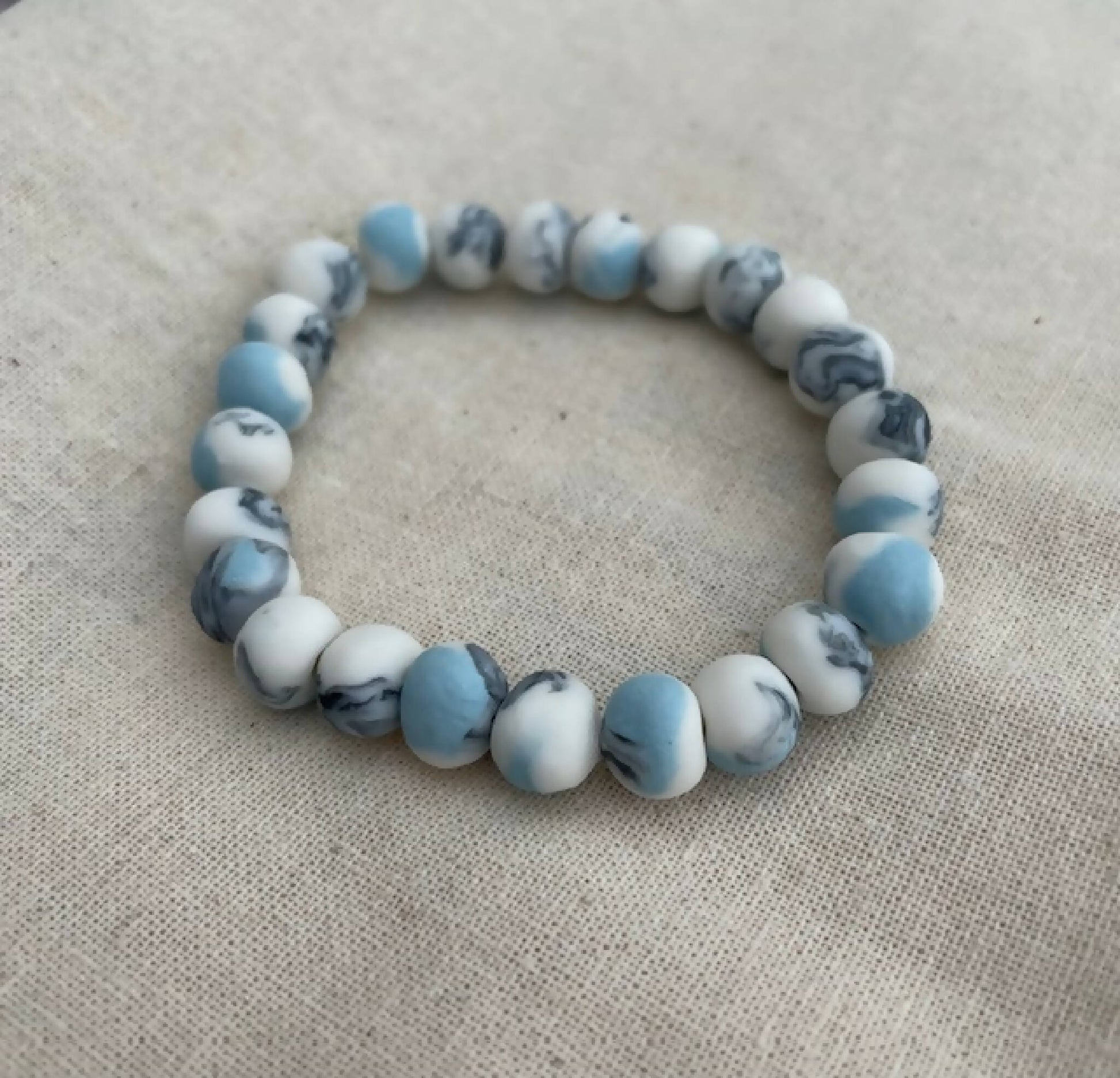 Bracelet femme en perles de porcelaine bleu clair et blanches, motif marbré.