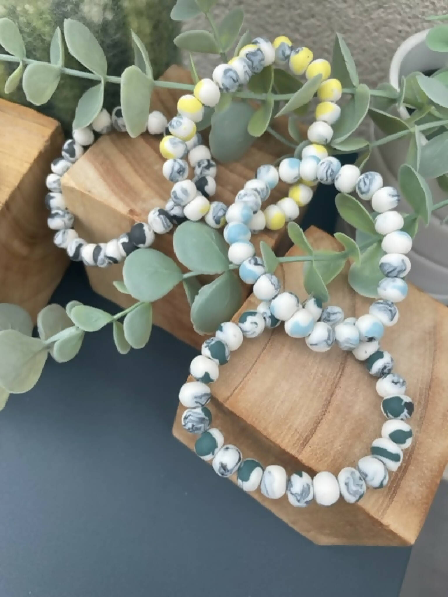 Bracelets en perles de porcelaine blanc, bleu clair et jaune, motifs marbrés.