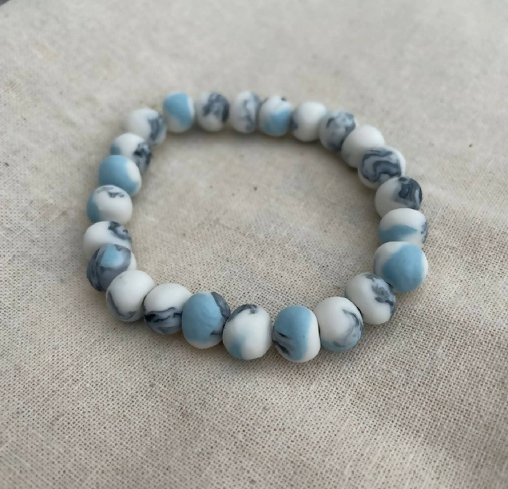 Bracelet femme en perles de porcelaine bleu clair et blanches, motif marbré.