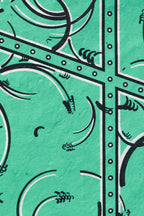 Détail de tissu vert émeraude, arabesques et cadre à picots sur motif géométrique