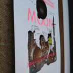 Affiche Moon avec visage et ville en silhouette, lettres rouges