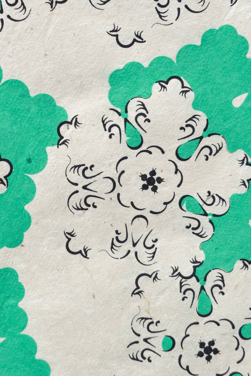 Papier décoratif vert et blanc à motifs floraux, gros plan sur une forme centrale.