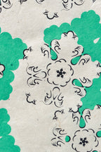 Papier décoratif vert et blanc à motifs floraux, gros plan sur une forme centrale.