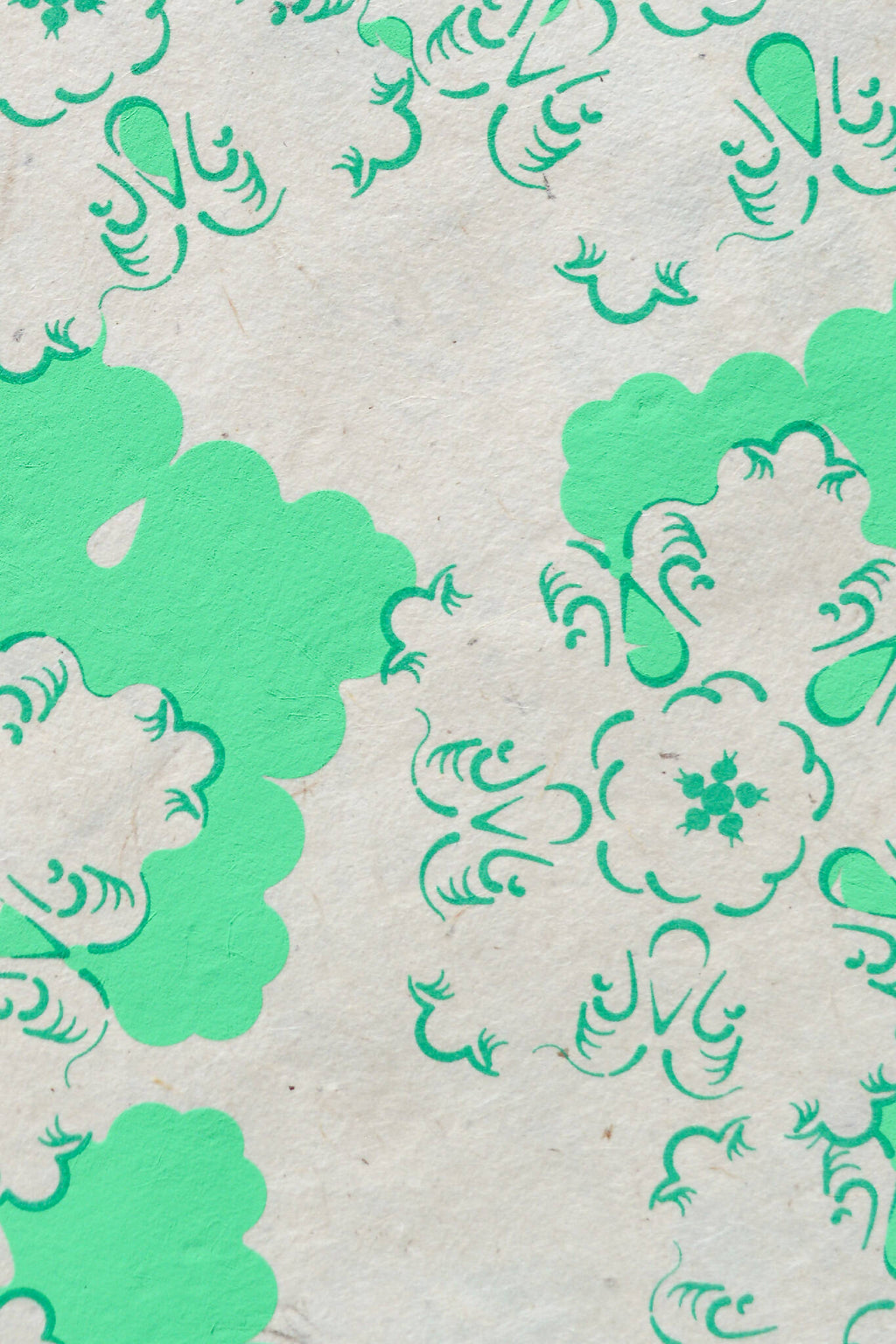 Papier décoratif vert et blanc, motifs floraux et volutes en gros plan.