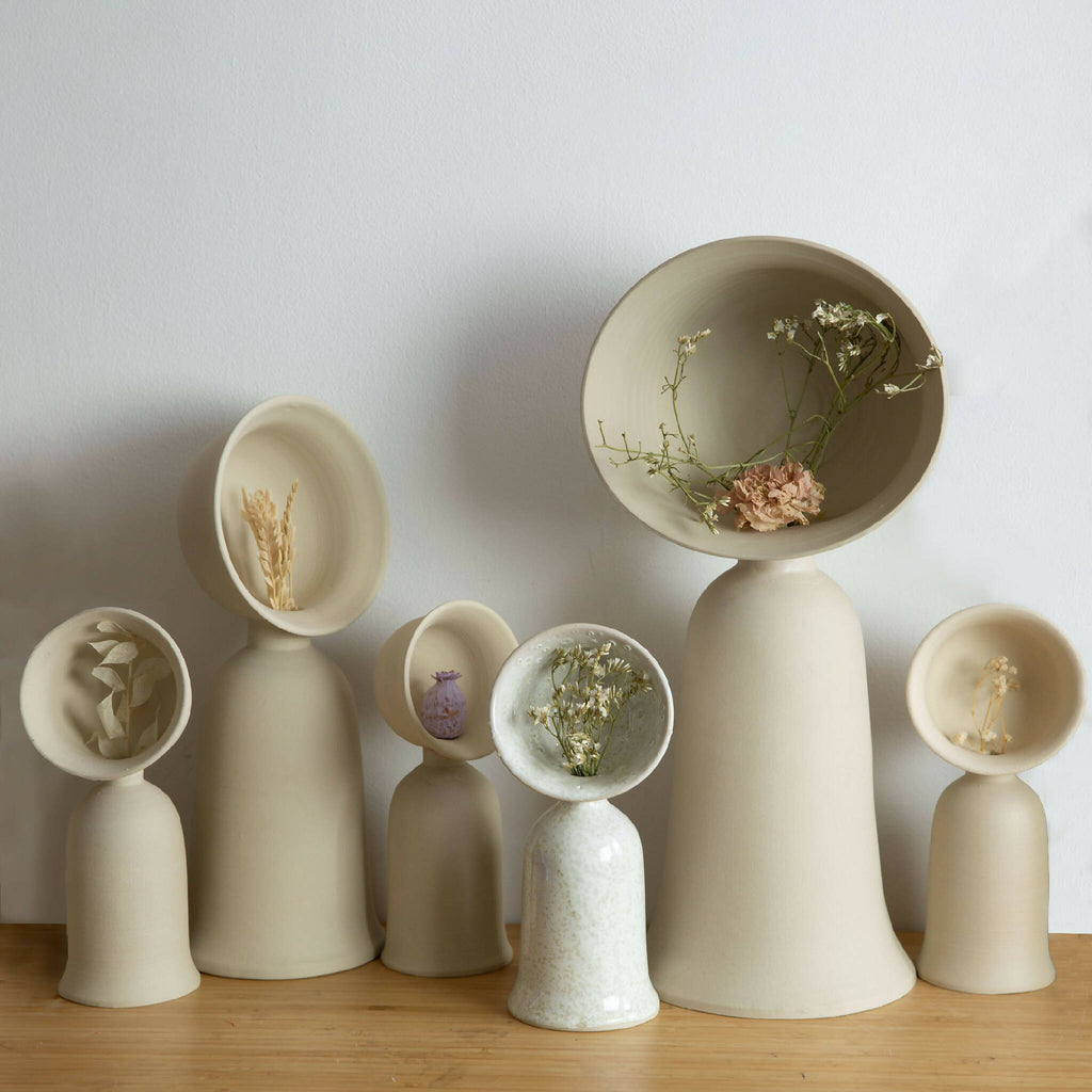 Ensemble de vases soliflores beige sur socles, bouquets de fleurs séchées.