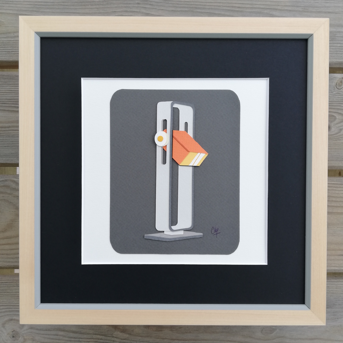 Lampe à poser grise avec abat-jour orange, dans un grand cadre rectangulaire