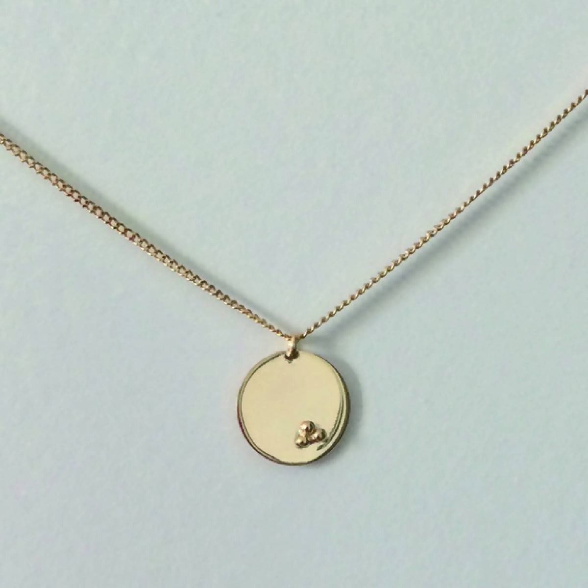 Collier doré à pendentif rond façon médaillon avec petit motif en relief