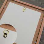 Lampe à poser avec cadre en bois clair au dos, attaches métalliques dorées visibles