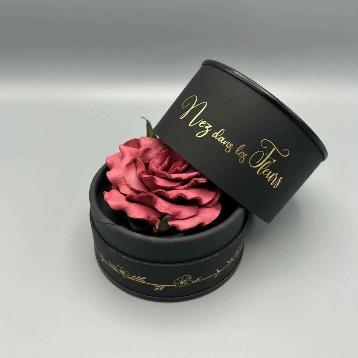 Boîte parfumée noire ouverte avec rose rose et couvercle en biais