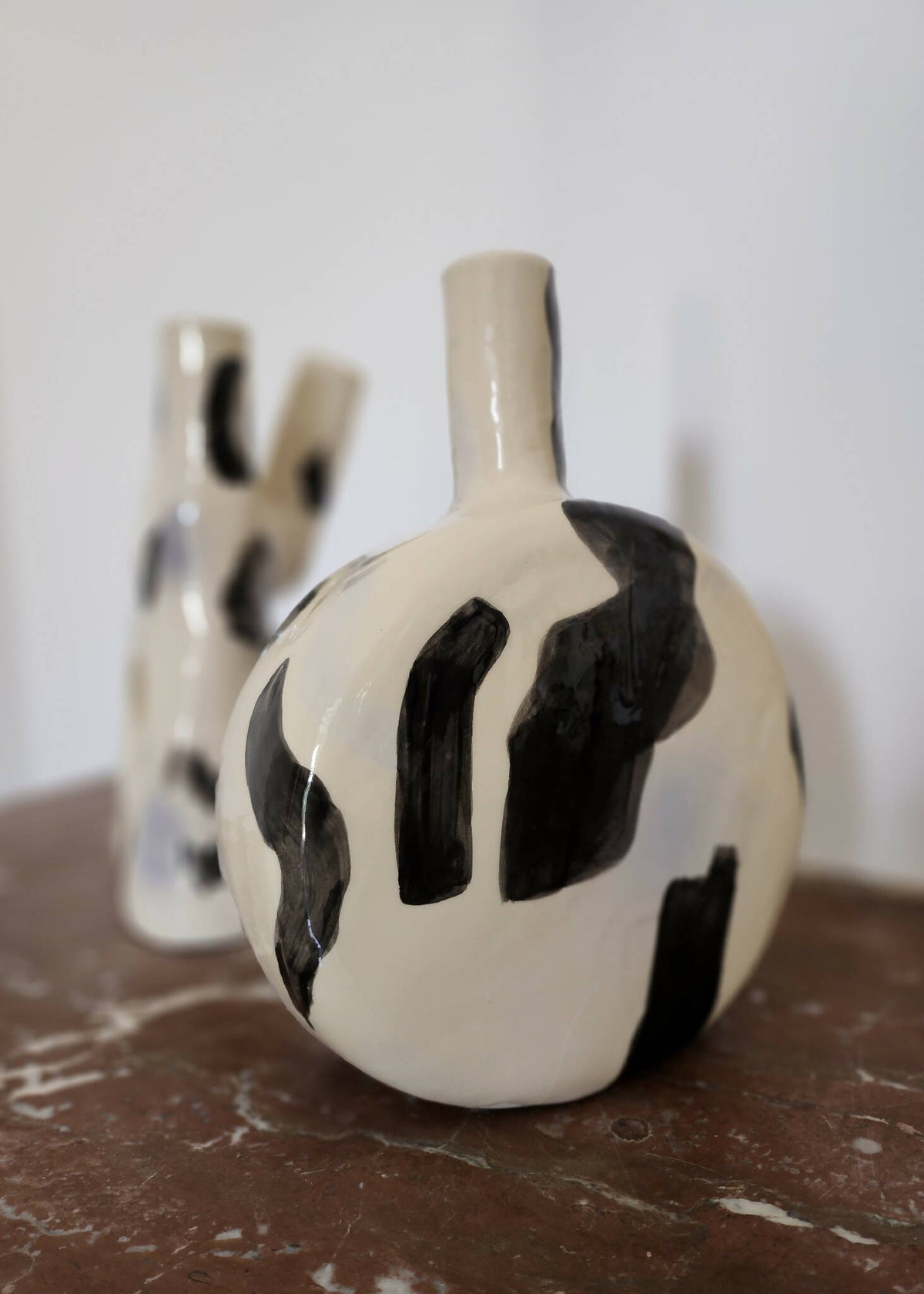 Vase en céramique crème avec motifs noirs et col étroit, forme boule