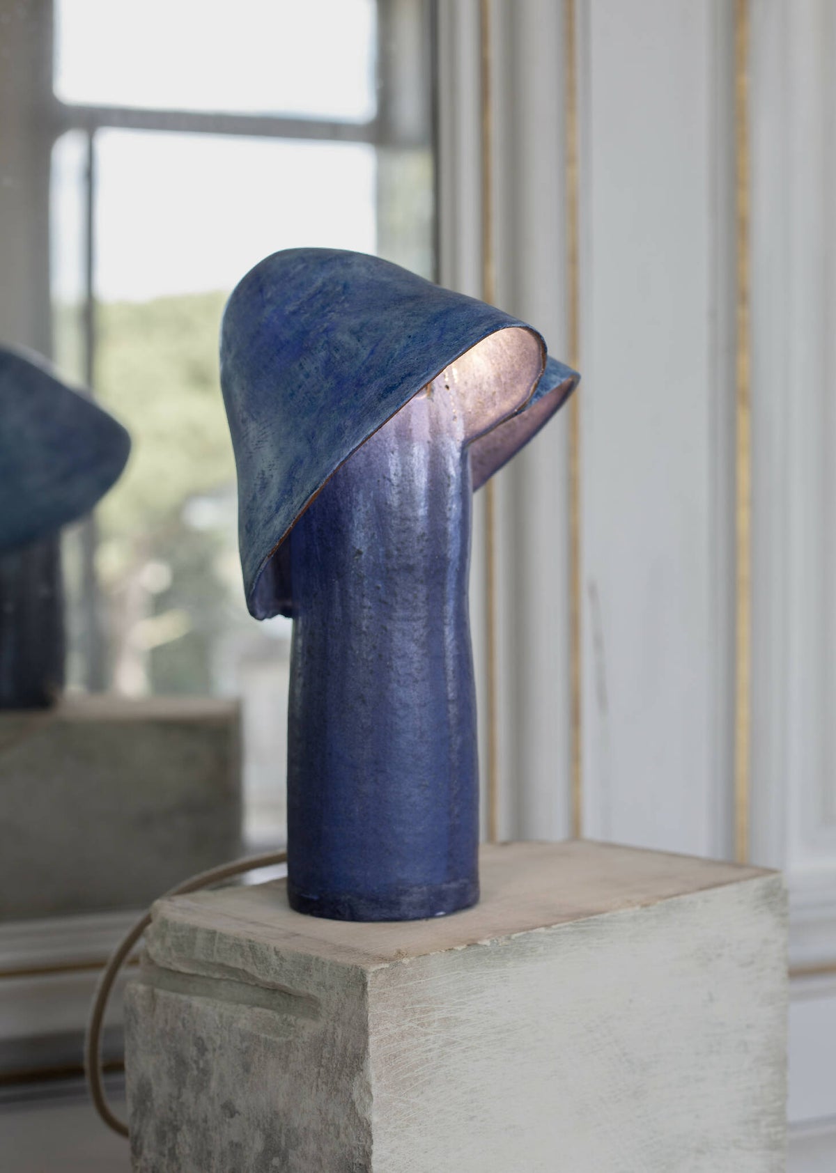 Lampe bleue à abat-jour conique sur socle rectangulaire, vue de côté