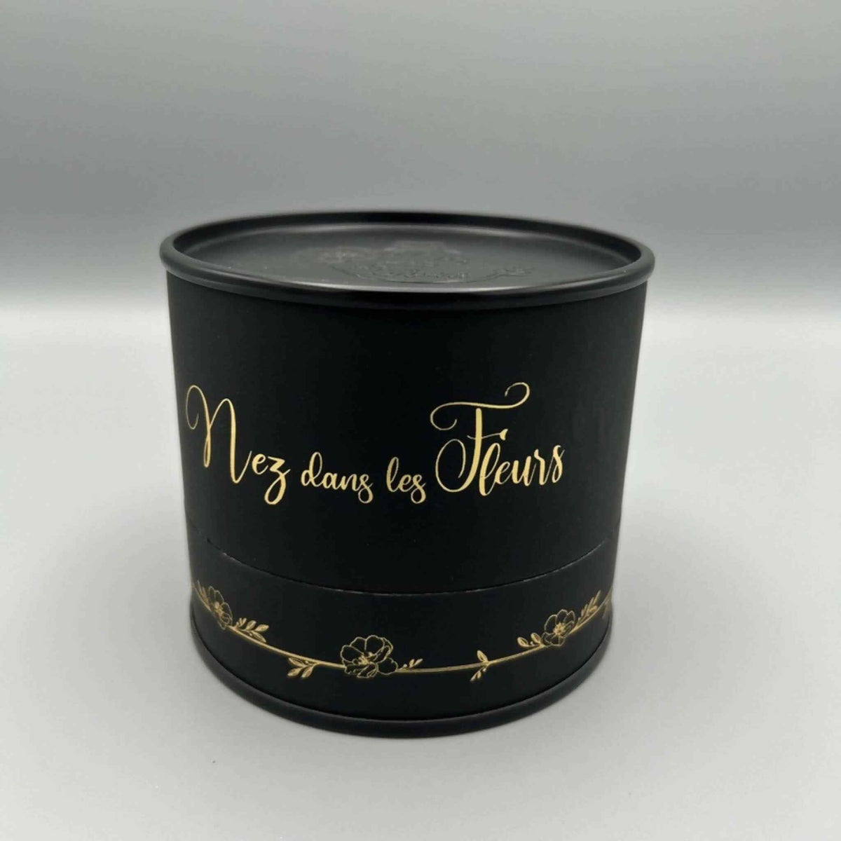 Boîte parfumée noire ronde avec couvercle et inscription dorée « Nez dans les Fleurs »