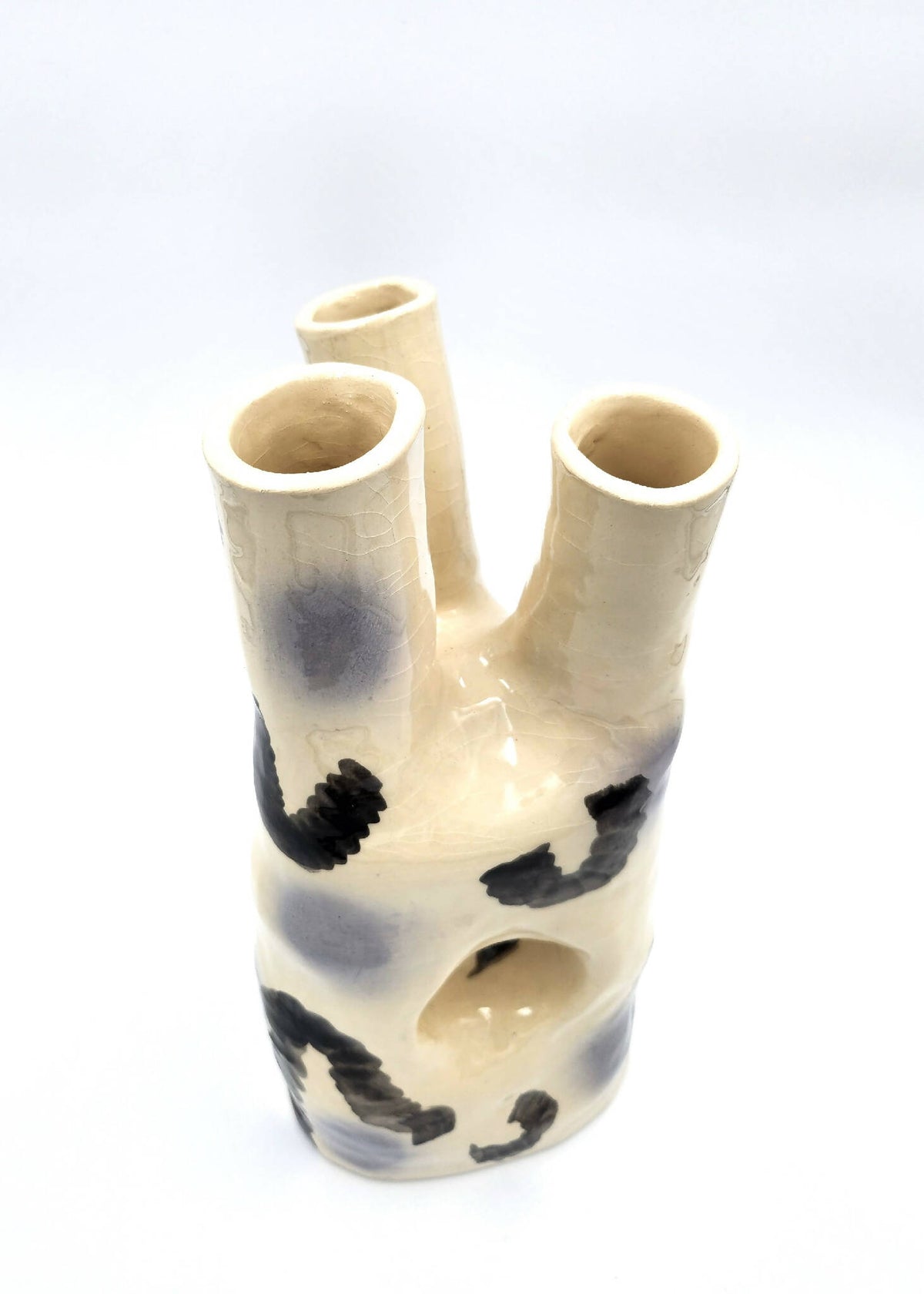 Vase en céramique crème avec trois ouvertures cylindriques et motifs noirs abstraits.
