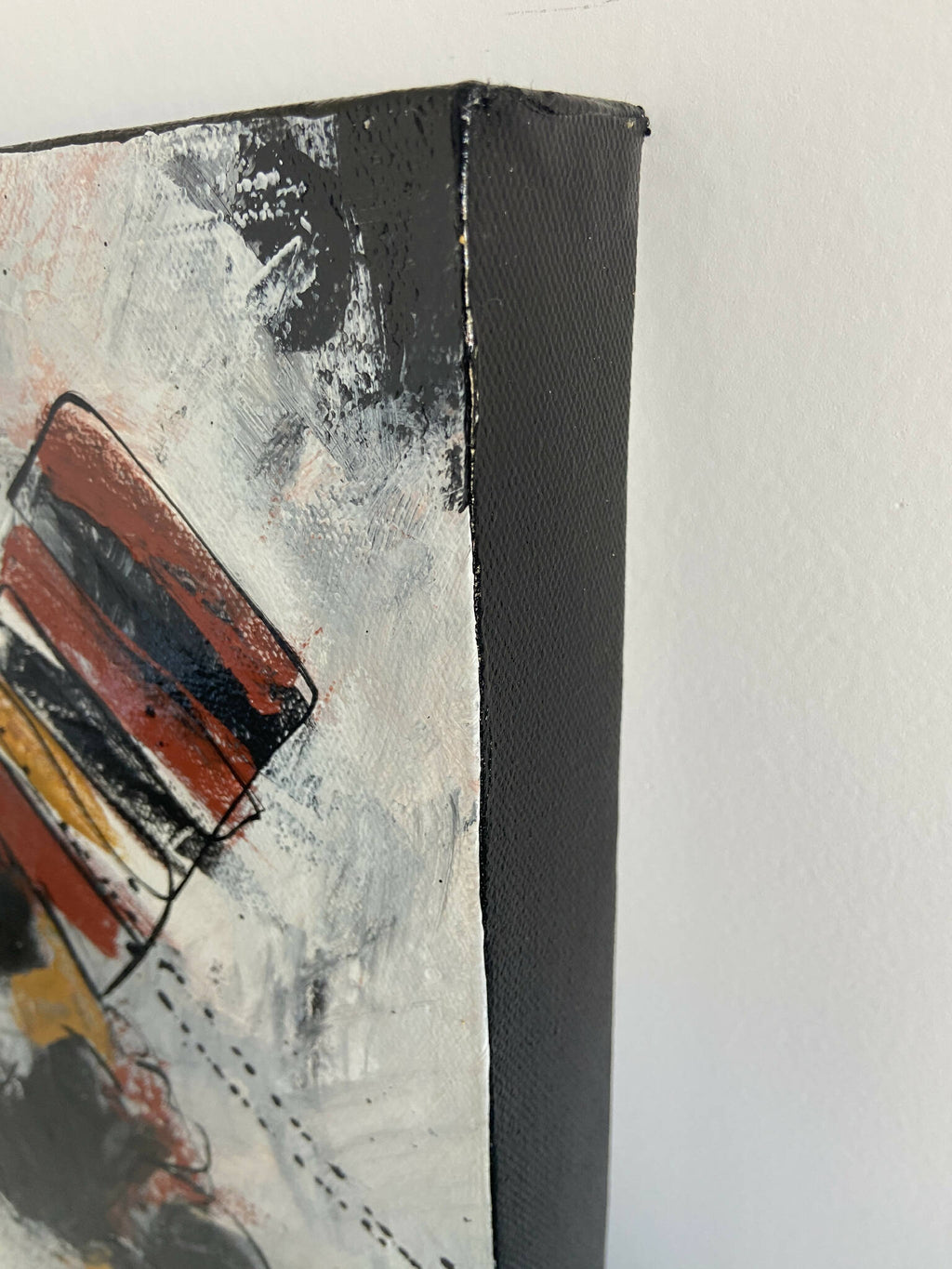 Toile abstraite, gros plan sur aplats rouge et noir, touches jaunes, côté sombre texturé.