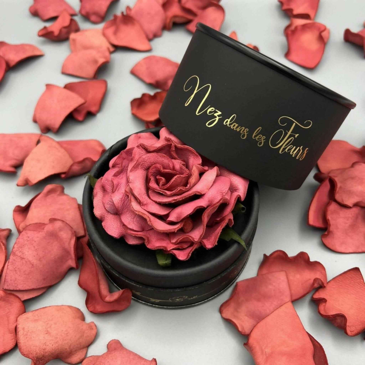 Boîte parfumée noire avec rose rose et pétales en cuir sur socle rond