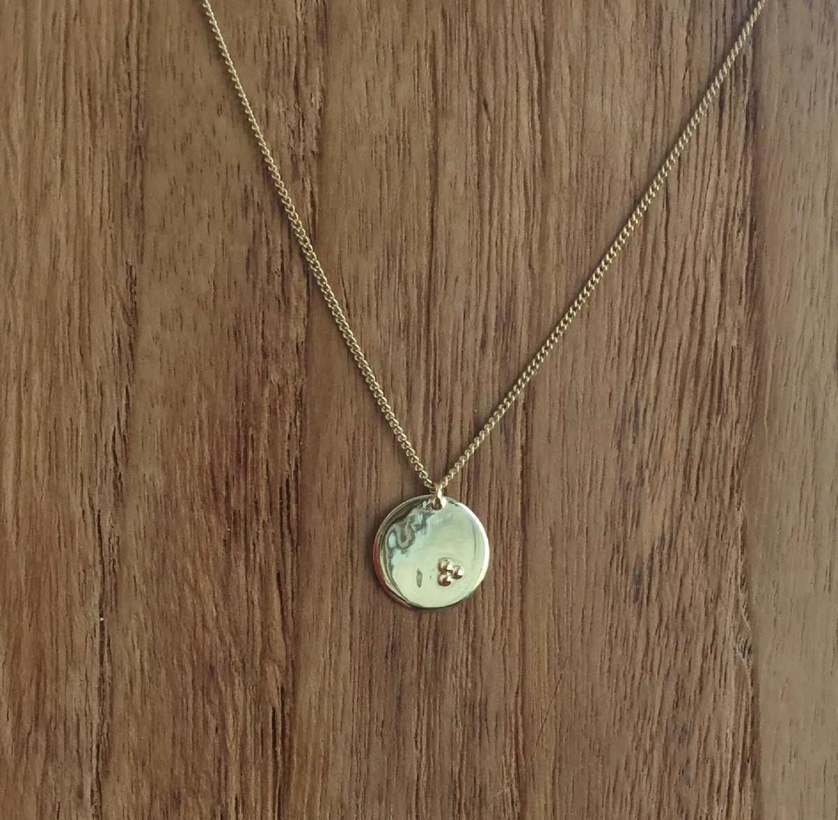 Collier à chaîne dorée et pendentif rond clair avec petit motif gravé