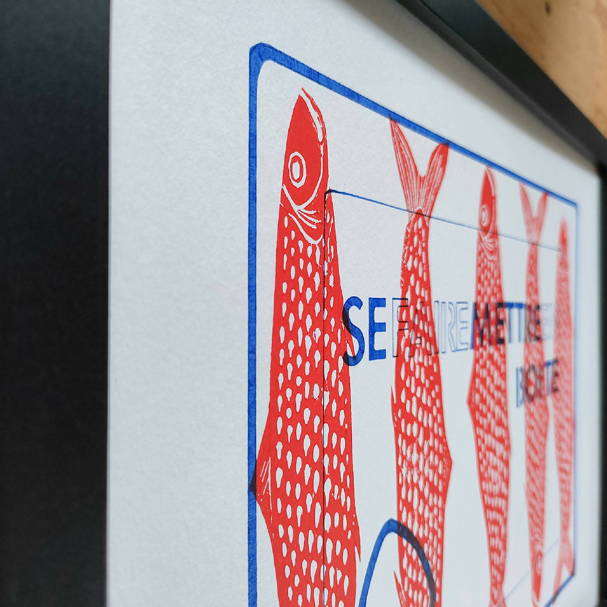 Gros plan d’une affiche encadrée : poissons rouges et motifs sur fond clair